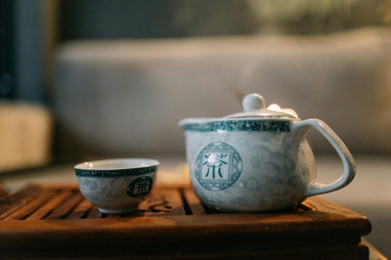 Elegantly designed porcelain teapot and cup set on a wooden tray, perfect for a serene tea ritual.